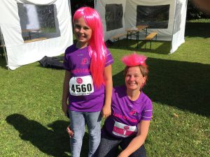 Muter und Tochter mit pinkfarbenen Perücken und Teilnehmer-T-Shirts