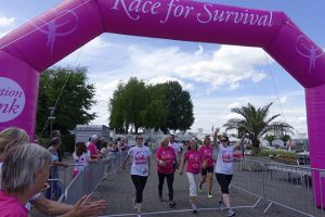 Läuferinnen mit pinkfarbenen T-Shirts laufen gut gelaunt in Köln ins Ziel