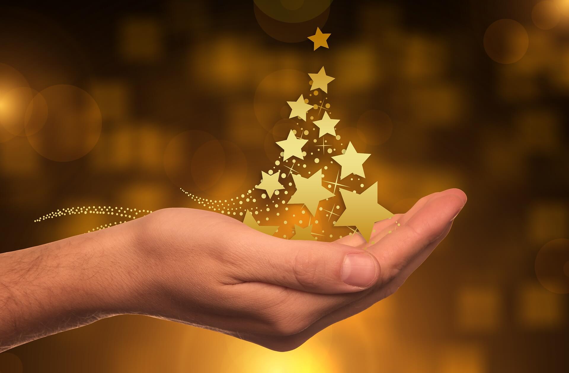 Hand hält Christbaum aus goldenen Sternen